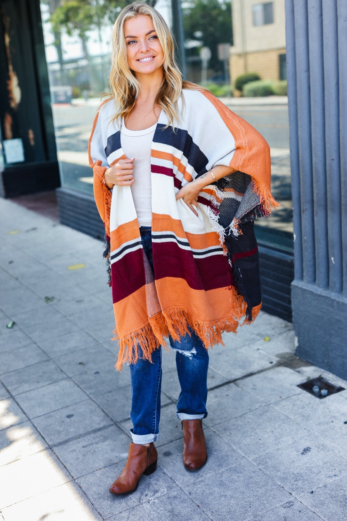 Zoe® | Follow Me Rust colored open poncho with multi colored stripes and tassel fringes